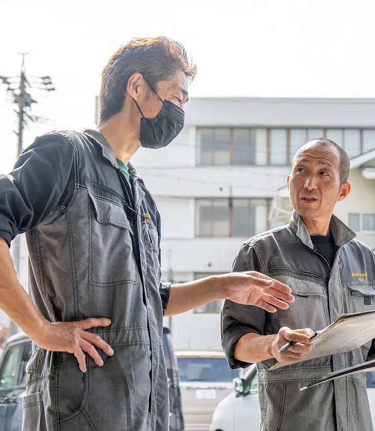 車のそばで打ち合わせをする社員