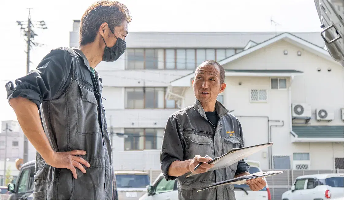 車のそばで打ち合わせをする社員